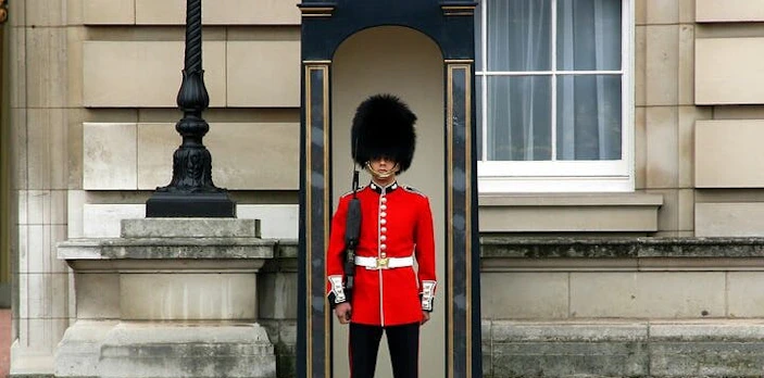 Royal guard in red uniform at Buckingham Palace during Changing of the Guard, London.