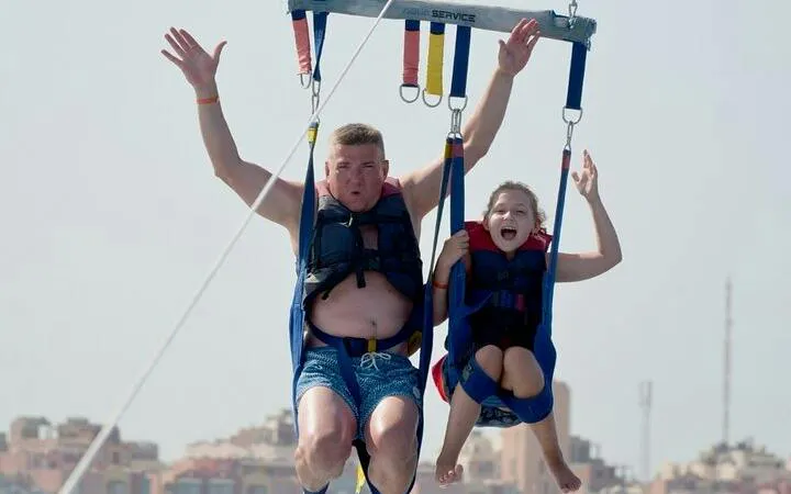 Parasailing adventure over the Red Sea in Hurghada with cityscape in the background.