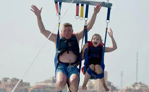 Parasailing adventure over the Red Sea in Hurghada with cityscape in the background.