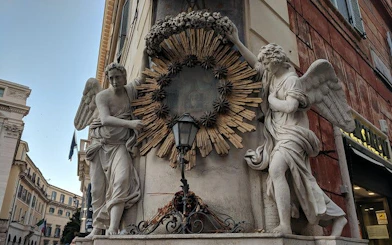 Angels statues on a building corner in Rome, part of the Angels & Demons city exploration game.