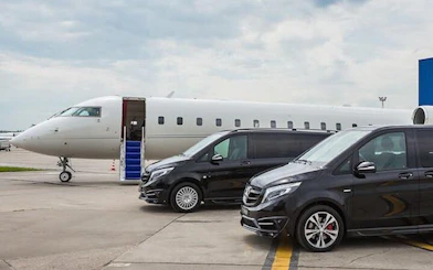 Private vans parked near a jet at Cappadocia airport for transfer service.