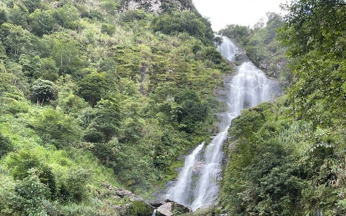 Waterfall surrounded by lush greenery on Sapa Motorbike Tour, Vietnam.