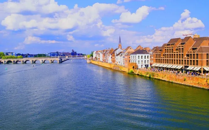 Maastricht riverfront with historic buildings and bridge on self-guided walking tour.