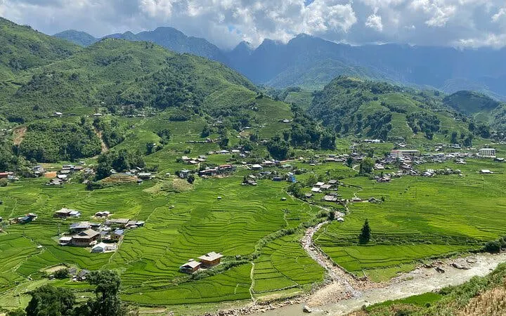 Sapa rice terraces and village on Y Linh Ho trail, Vietnam, with mountains in the background.