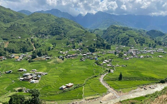 Sapa rice terraces and village on Y Linh Ho trail, Vietnam, with mountains in the background.