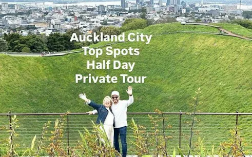 Couple enjoying view from Mount Eden with Auckland cityscape in background.
