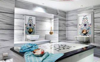 Turkish bath interior with marble slabs, decorative basins, and towels in Istanbul.
