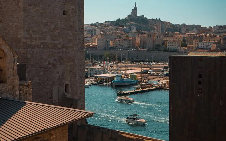 Marseille harbor view with boats and Notre-Dame de la Garde basilica in the background.
