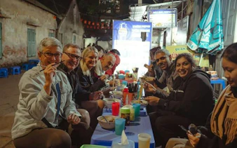 Group enjoying street food at a local eatery during Hanoi E-Scooter City Tour.