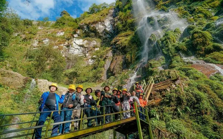 Group on a bridge near Queen Bee Waterfall during Sapa motorbike and jungle trek tour.