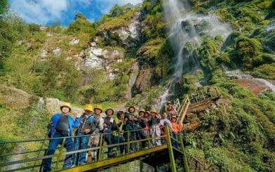 Group on a bridge near Queen Bee Waterfall during Sapa motorbike and jungle trek tour.