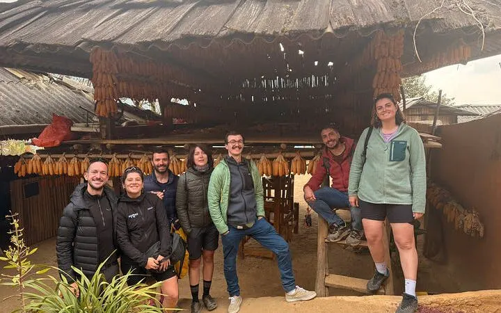 Group of tourists at a traditional wooden house in Mu Cang Chai, Vietnam, during a private car tour.