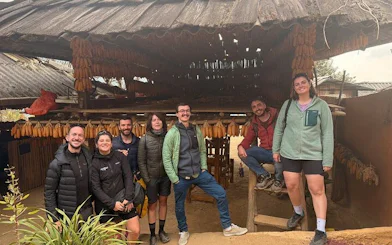 Group of tourists at a traditional wooden house in Mu Cang Chai, Vietnam, during a private car tour.