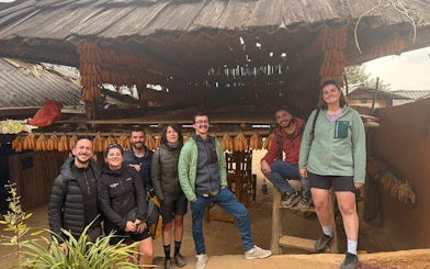 Group of tourists at a traditional wooden house in Mu Cang Chai, Vietnam, during a private car tour.