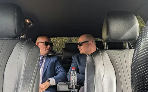 Private car interior with two drivers in suits for Bucharest Otopeni Airport transfer.