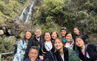 Group of tourists at a waterfall in Sapa during a private car tour to Lonely Tree and Heaven's Gate.