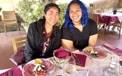 Tuscany wine tour guests enjoying traditional lunch with cured meats and wine.