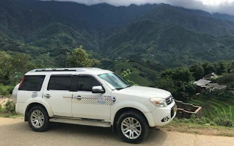 Private car on scenic route from Sapa to Ha Giang City with terraced rice fields.