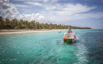 Catamaran cruising near Punta Cana's palm-lined shore in clear turquoise water.