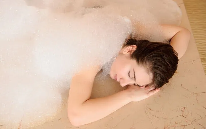 Person relaxing under foam during Turkish bath in Sharm El Sheikh spa.