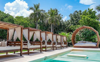Poolside cabanas at Isla Mujeres beach club with palm trees in the background.
