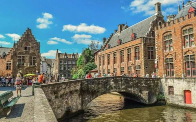 Bridge over canal with historic buildings in Bruges, Belgium, part of day trip from Brussels.