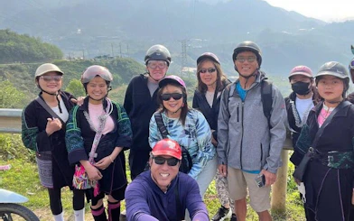 Group of tourists on a motorbike tour in Sapa, Vietnam, with scenic mountain backdrop.