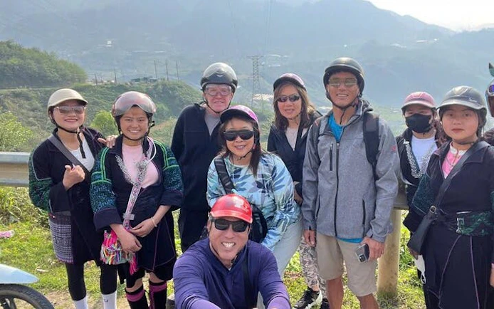 Group of tourists on a motorbike tour in Sapa, Vietnam, with scenic mountain backdrop.