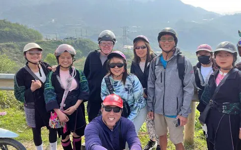 Group of tourists on a motorbike tour in Sapa, Vietnam, with scenic mountain backdrop.