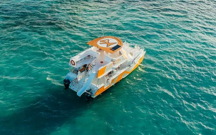 Catamaran with slide on turquoise water, Punta Cana snorkeling cruise.