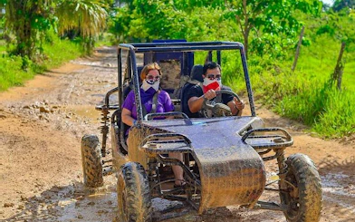 Two people driving a buggy on a muddy trail during a Punta Cana jungle tour.