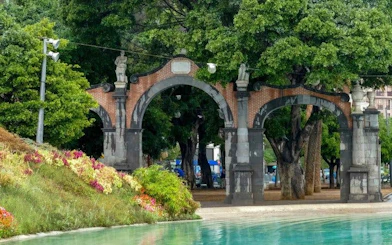 Arched entrance in a park with trees and a pond, part of Tenerife self-guided walking tour.