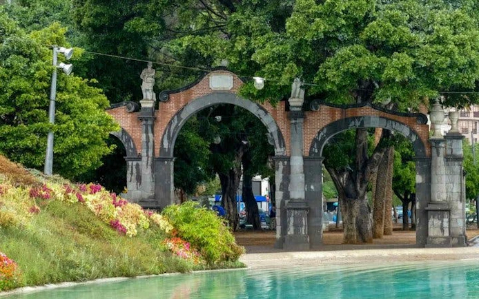 Arched entrance in a park with trees and a pond, part of Tenerife self-guided walking tour.