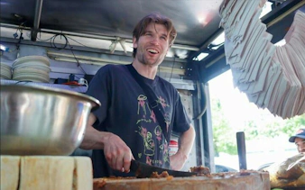 Man preparing tacos at a street food stall in Mexico City.