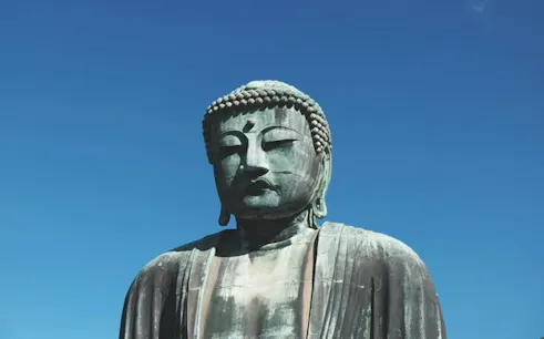 Great Buddha statue in Kamakura under clear blue sky.