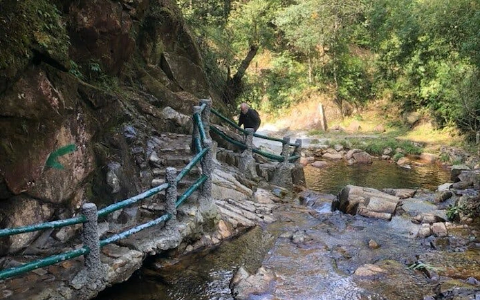 Motorbike tour path near stream in Sa Pa, Vietnam, with rocky terrain and lush greenery.