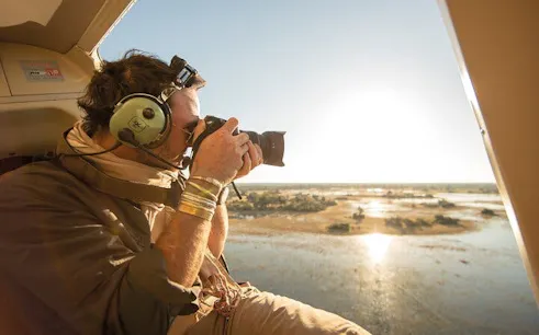 Photographer capturing Okavango Delta from helicopter during 45-minute tour.