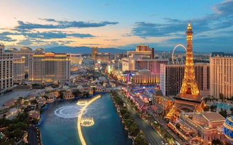 Las Vegas Strip skyline with illuminated Eiffel Tower replica and Bellagio fountains at dusk.