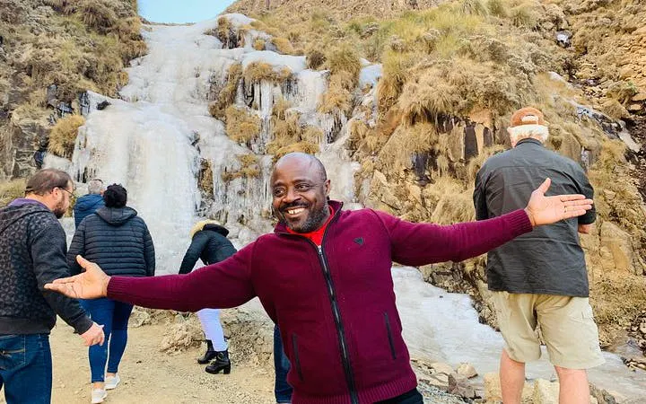 Group exploring icy waterfall on Sani Pass tour from Durban to Lesotho.