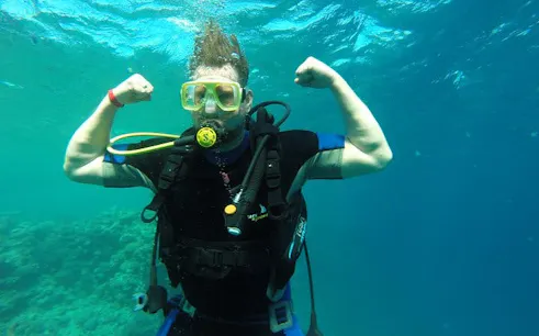 Scuba diver flexing underwater during Hurghada boat trip for beginners.