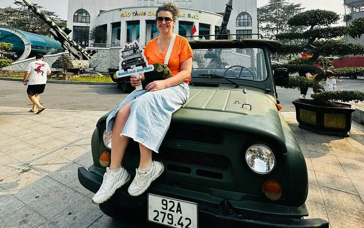 Woman sitting on a vintage jeep in front of the Vietnam Military History Museum, Hanoi.