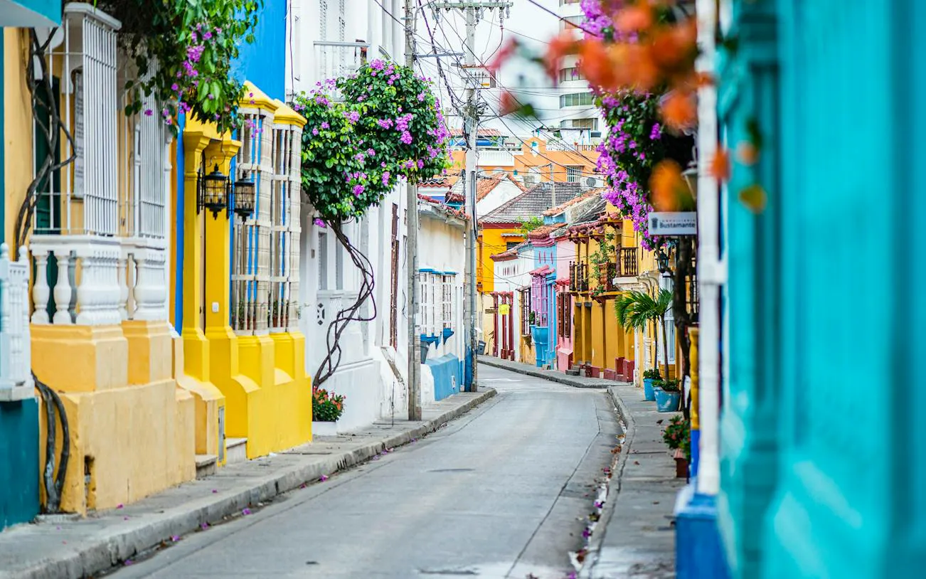 Colorful colonial street in Cartagena Walled City, featuring vibrant buildings and flowering vines.