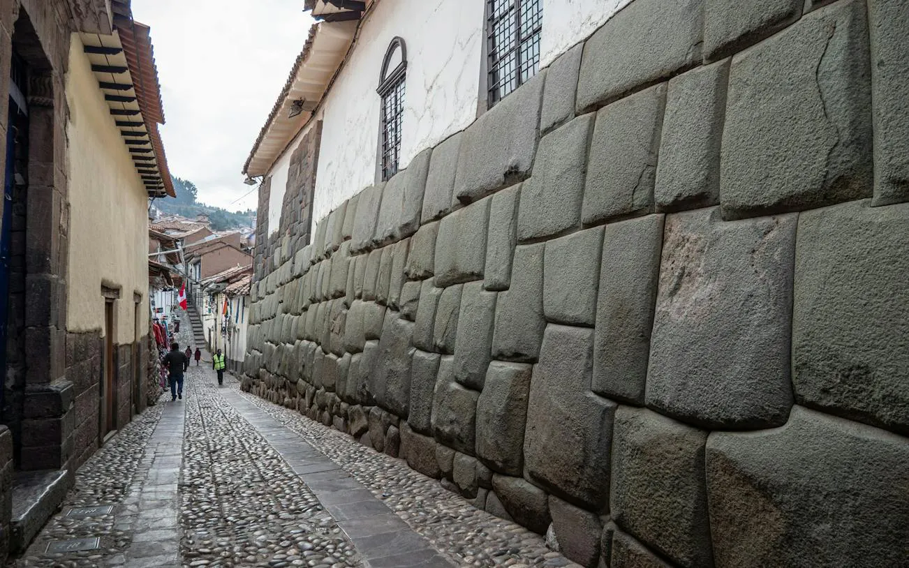 Narrow cobblestone street with Inca stone wall in Cusco Historic Center, Peru.