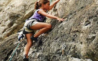 Child rock climbing on Railay Beach cliffs in Krabi, Thailand.