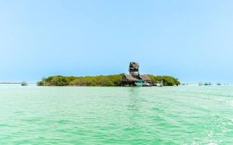 Holbox Island tour with view of Punta Mosquito's turquoise waters and rustic buildings.