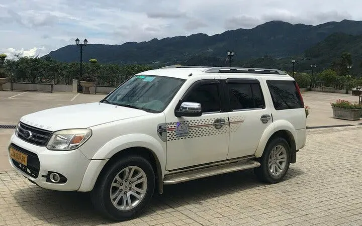 Private transfer vehicle for Sapa to Lào Cai Train Station with mountain backdrop.