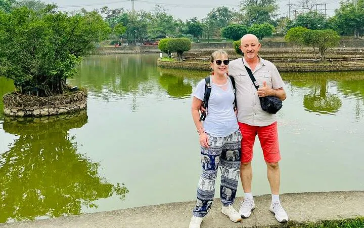 Couple posing by a pond at Co Loa Citadel during Hanoi countryside Vespa tour.