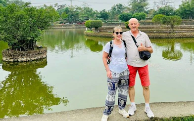 Couple posing by a pond at Co Loa Citadel during Hanoi countryside Vespa tour.
