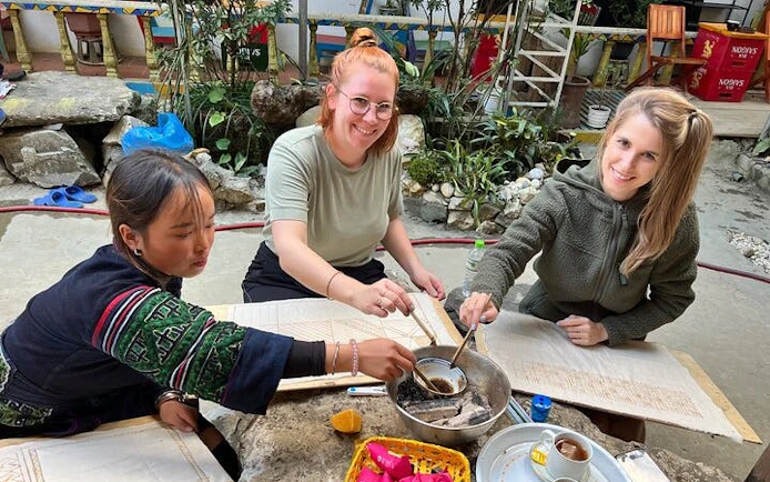 Local artisans and visitors creating batik art with beeswax in Sa Pa workshop.