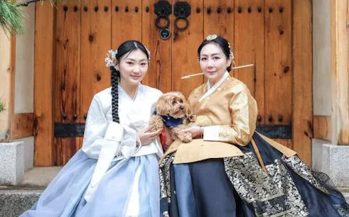 Women in traditional hanbok with a dog at Gyeongbokgung Palace, Seoul.